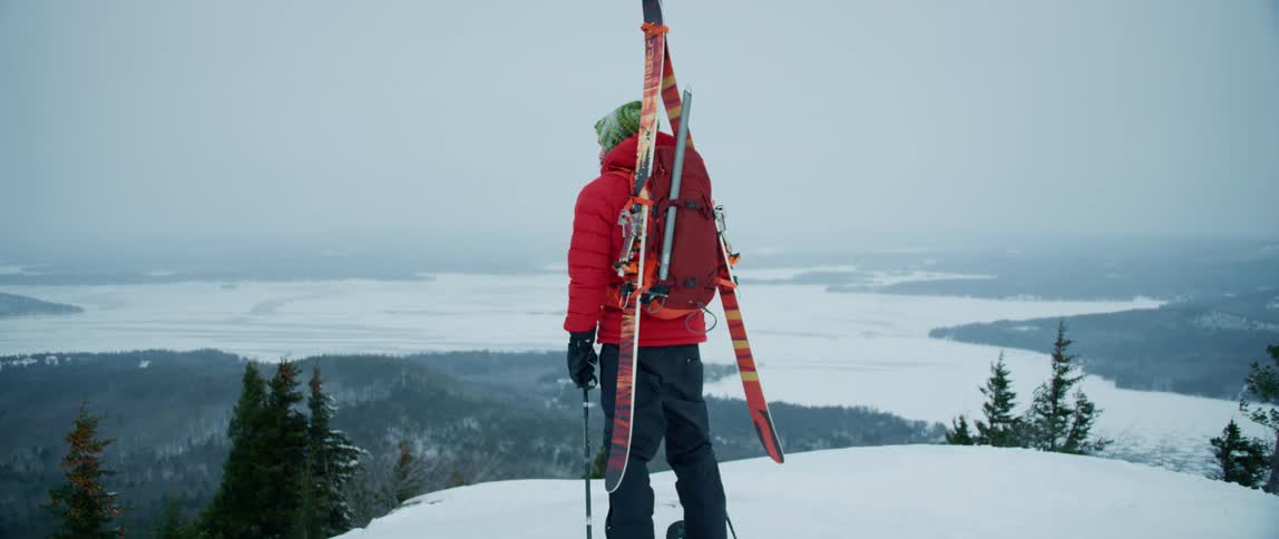 An Outdoorsman reaches the summit overlooking a vast wintery countryside