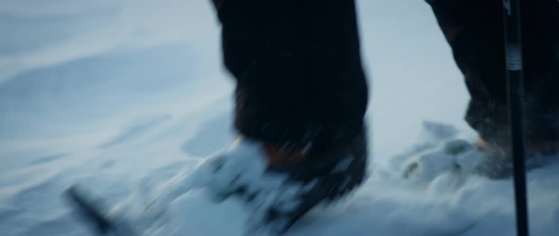 A hiker snowshoes across frozen snowy terrain