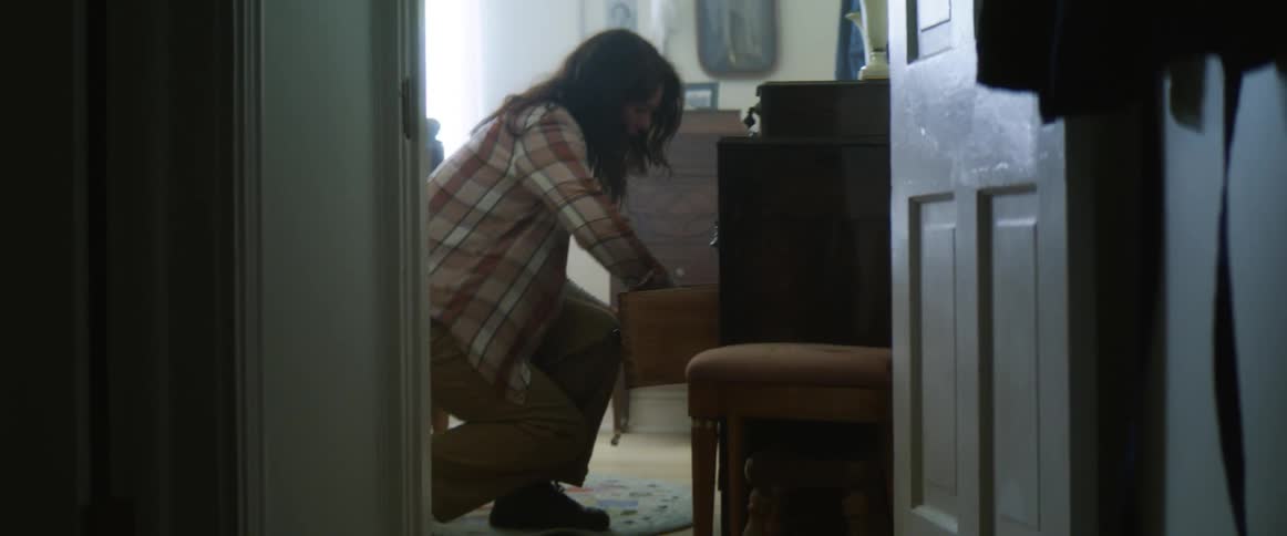 Woman rushing down hallway grabbing a blanket from drawer in bedroom