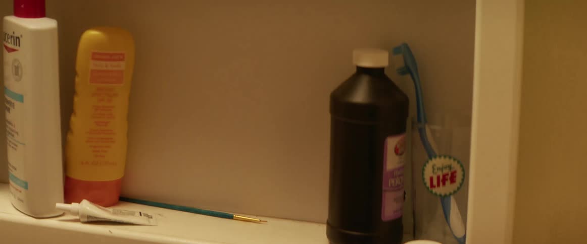 A woman frantically pulls items out of the medicine cabinet in her bathroom