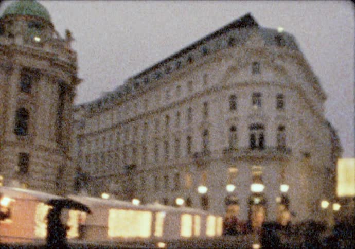 People walk around the Hofburg Palace in Vienna at dusk during Christmas time