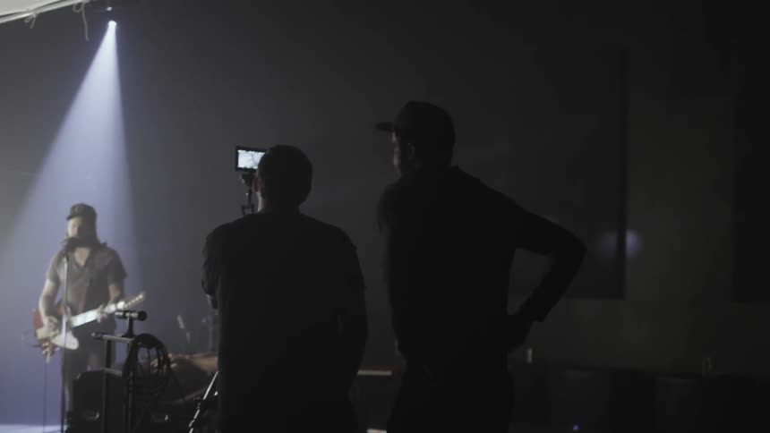 People are filming as others are playing instruments on stage