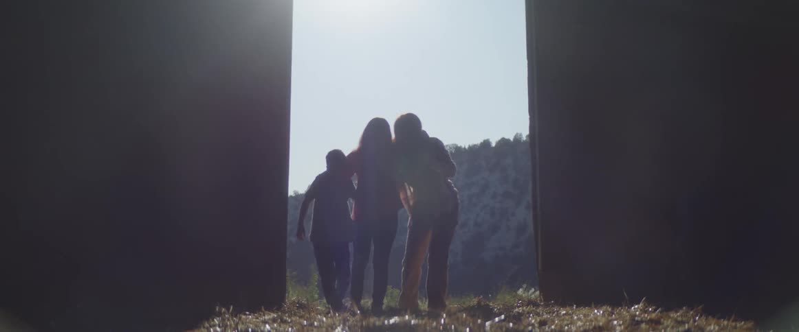 A woman opens a barn door and goes to help carry another woman inside