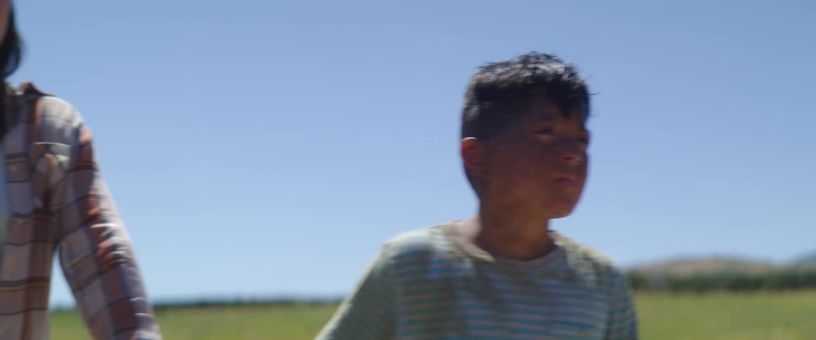 A little boy walks along holding a teenagers hand and then lets go and runs off