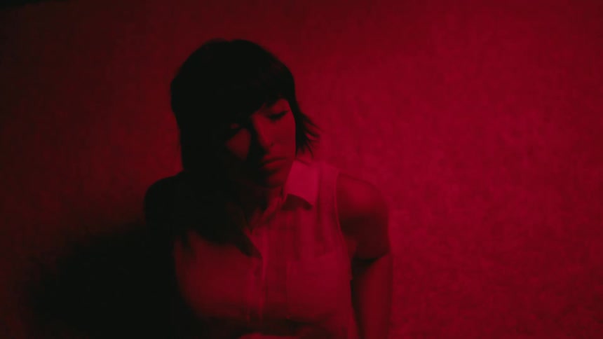 Woman leans back in red light tinted room