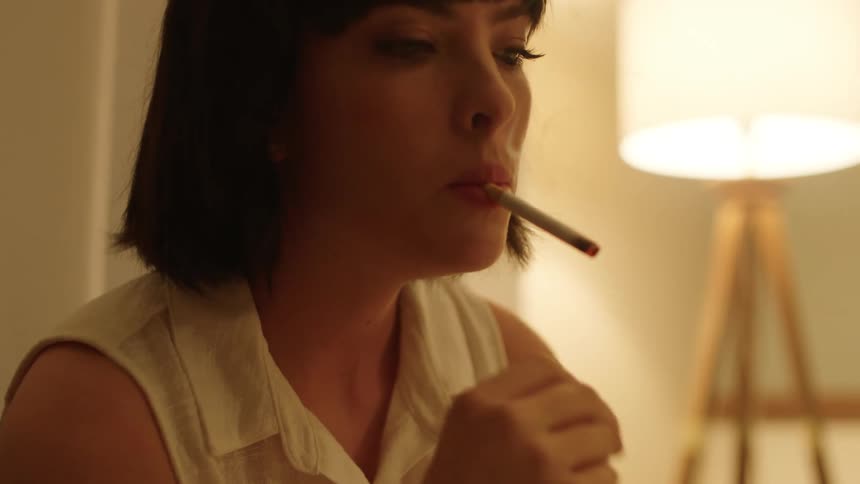 cigarette dangling Woman lights a cigarette then removes the cigarette from her mouth