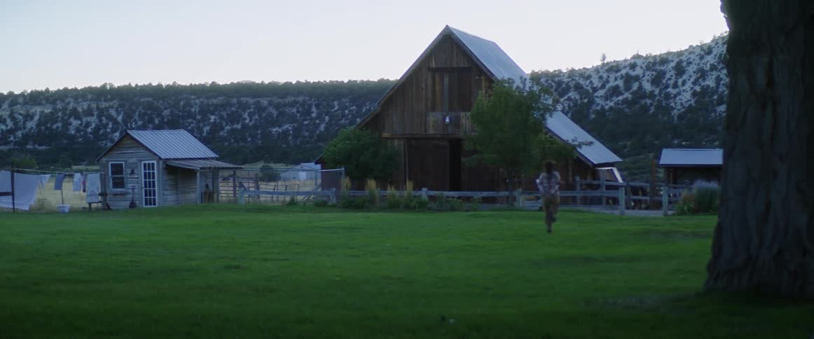 Woman runs towards a house in a farm at morning