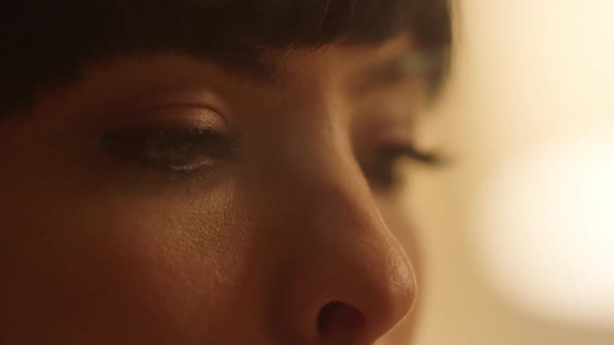 Woman with dark short hair smokes a cigarette at home