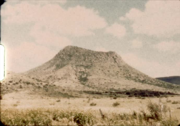 A mesa stands above desert grasslands