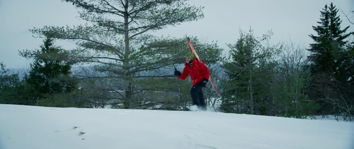 An outdoorsman trudges through deep snow as he hikes through the wilderness