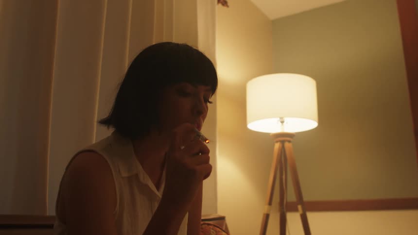 A woman is smoking in the bedroom