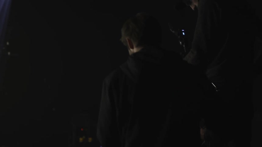 People are playing instruments on stage as a cameraman films