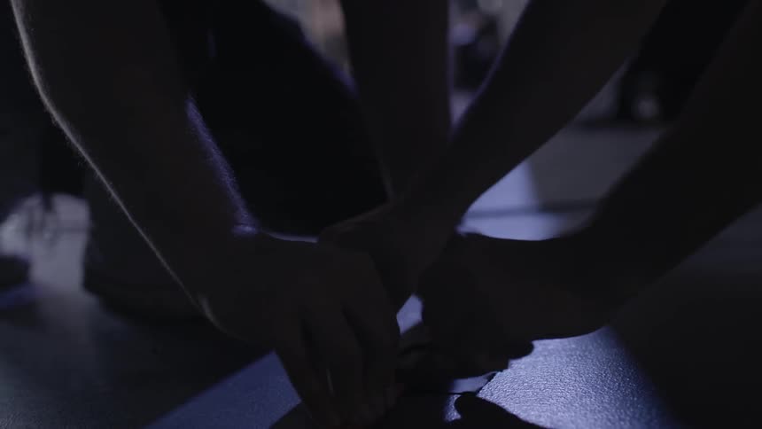 Two people are taping some wires to the ground