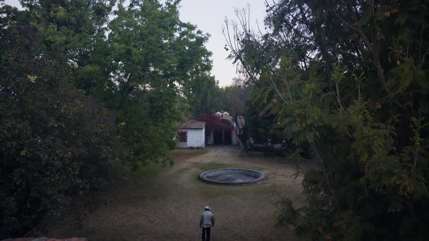 A man walks across a countryside area towards a shed