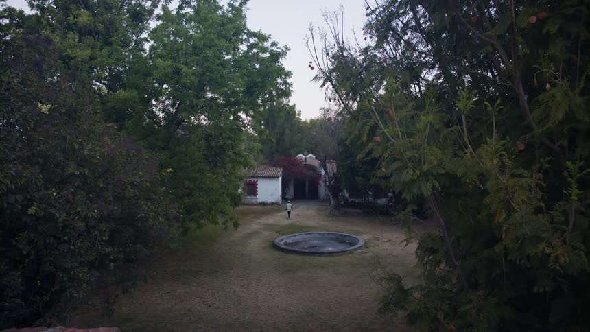 A person walks towards their home in the large yard
