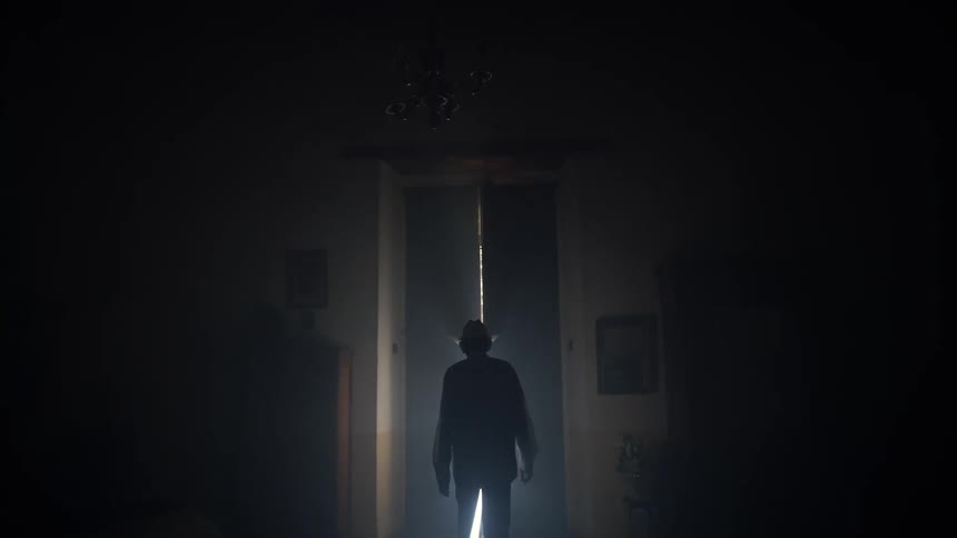 Elderly man walks towards doors then opens a door to reveal a bright light