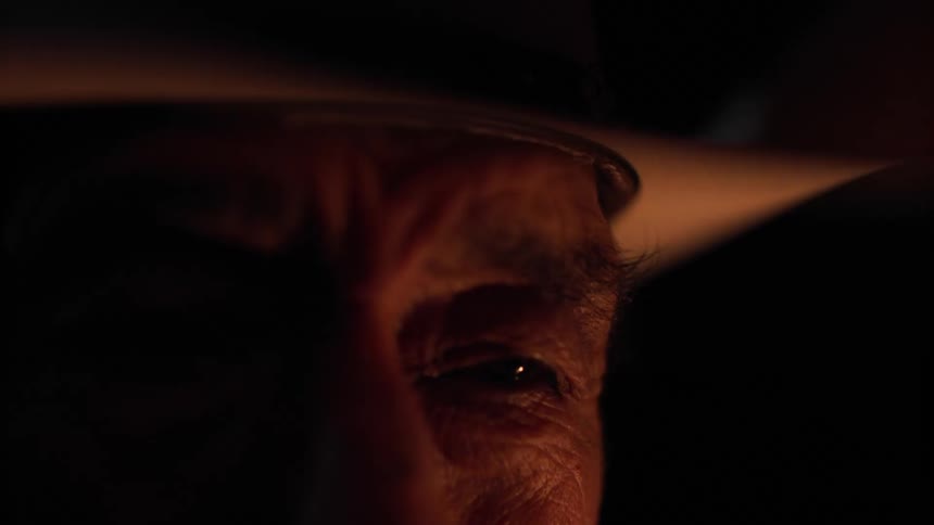 The light from a fire is flickering on the mans face