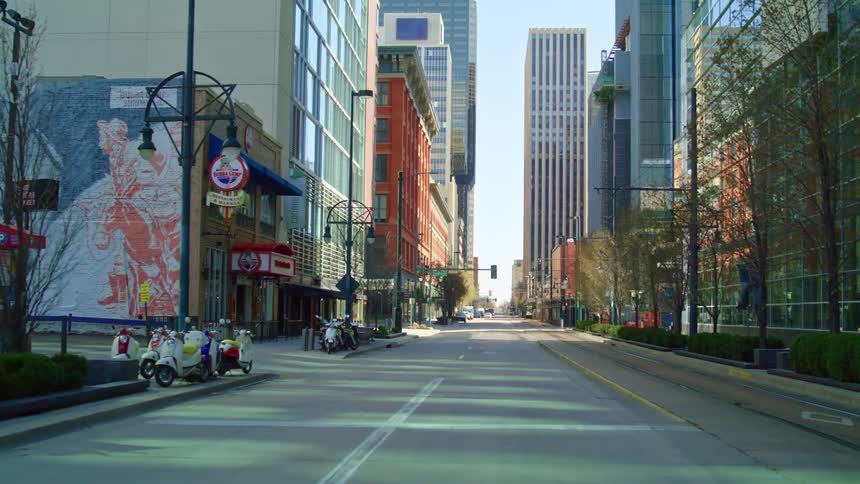 A city street with trees signs streetlights and buildings in the background