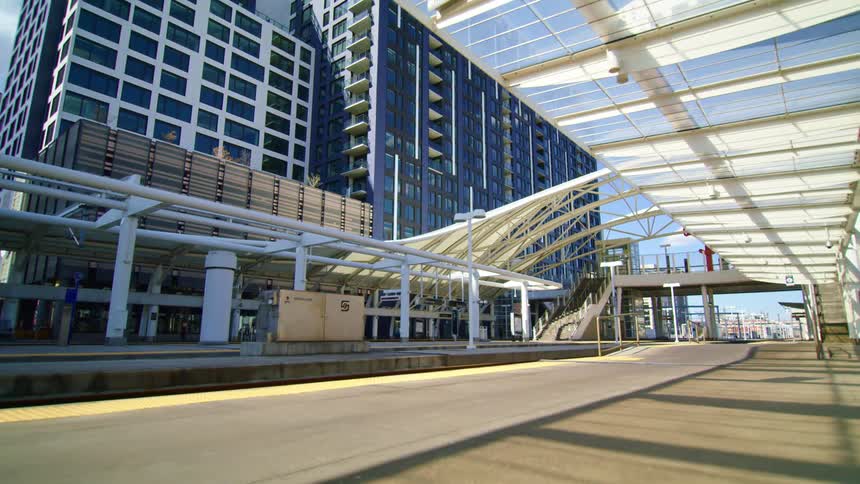 Buildings in a city sit next to the road under a blue sky