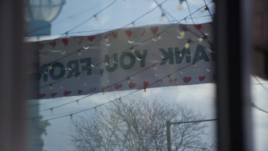 A man hangs an open sign on the glass door of his business