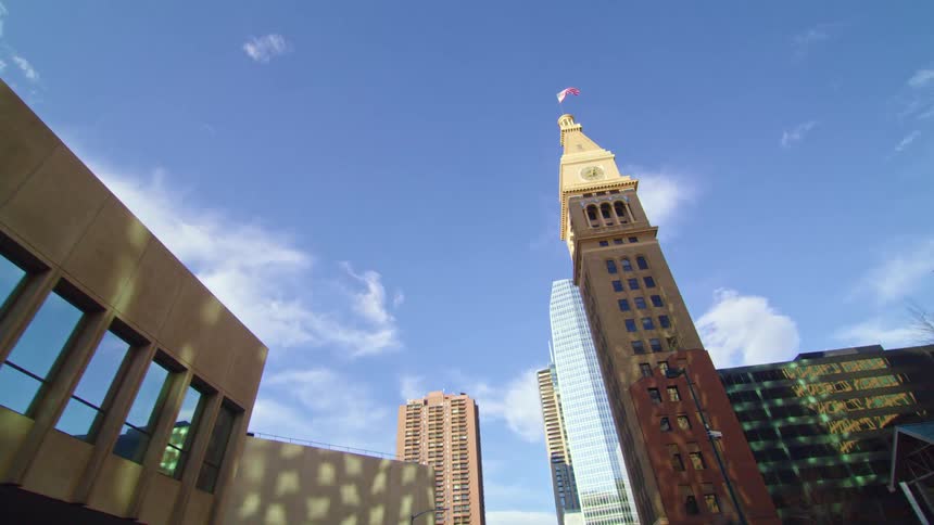 A skyscraper doubling as a clocktower in a metropolis on a sunny day