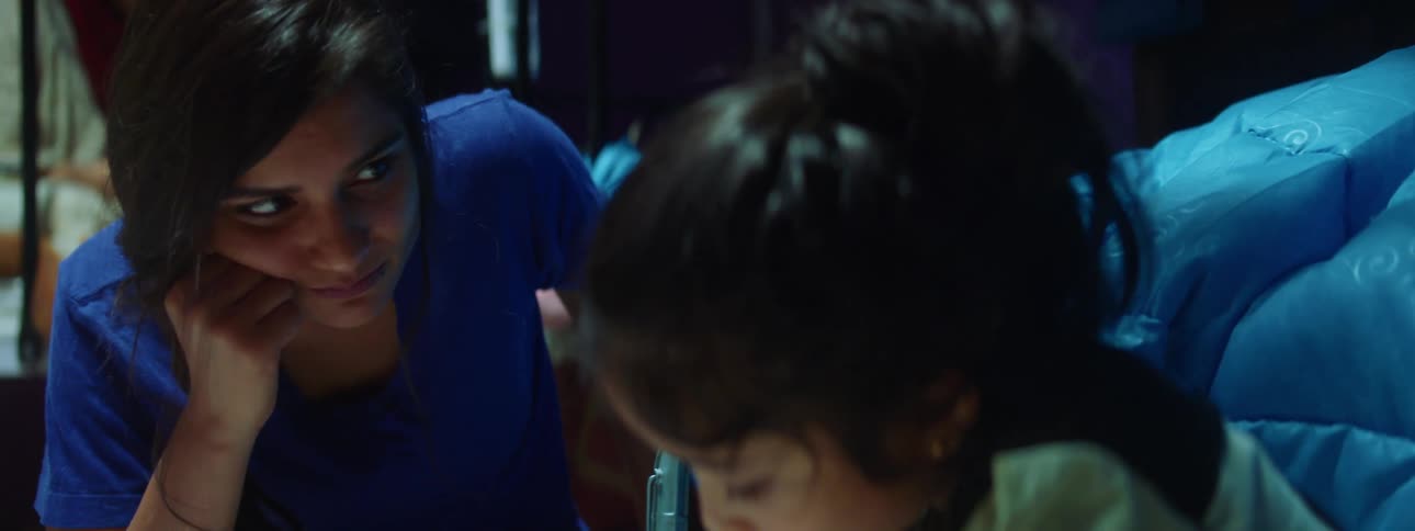 A woman sits and watches her daughter