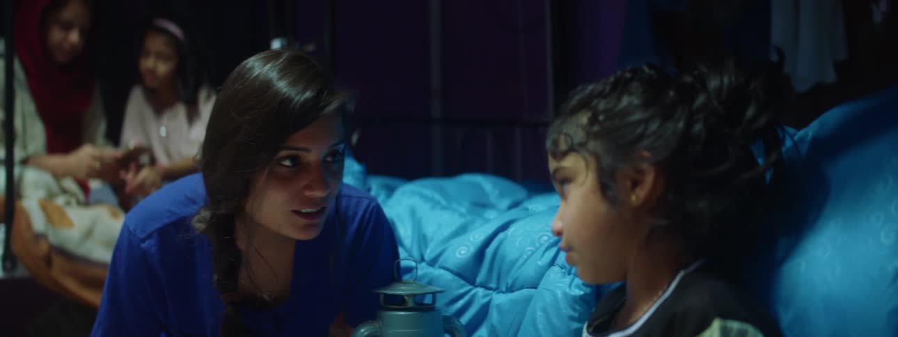 A woman and child sit on the floor doing school work