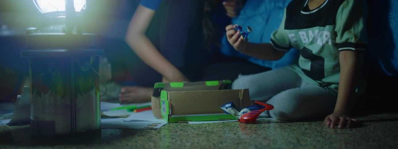 A child sits on the floor playing with toys with the light from a lamp