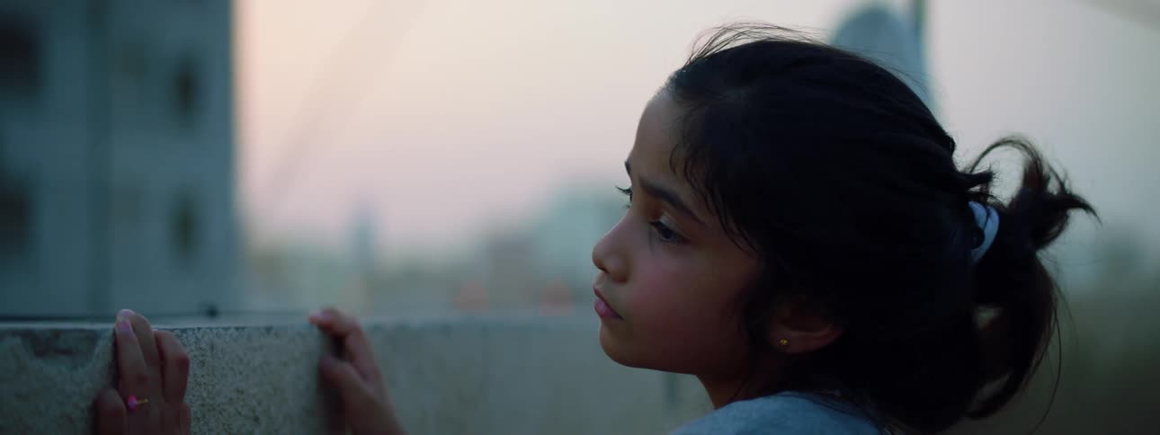 Girl touches wall looking over it near apartment building