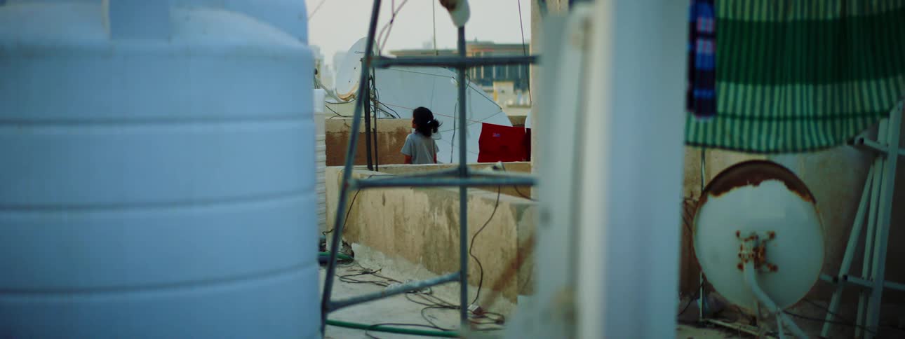 A young woman fidgets while standing on the roof of a building