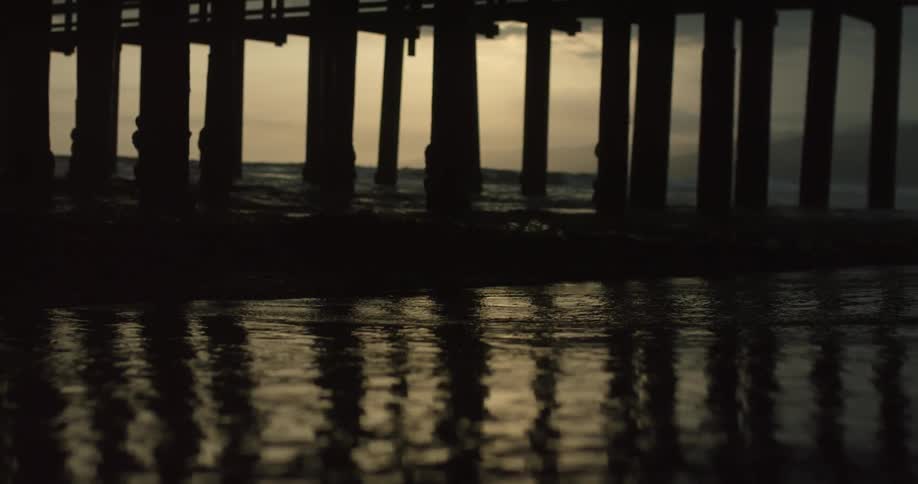 Tidal waters rolling ashore beneath a pier