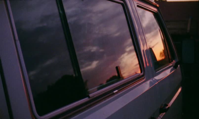 A person opens the sliding door of a van and pokes their hooded head outside of the door