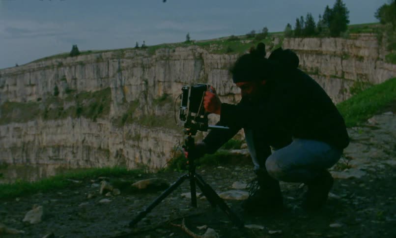 A person sets up a tripod and camera on a mountain top