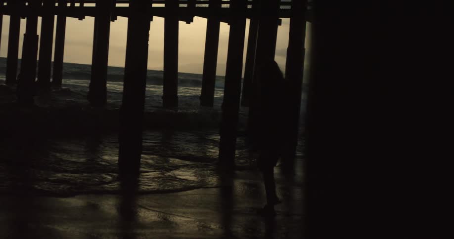 A person walks on the beach at sunset
