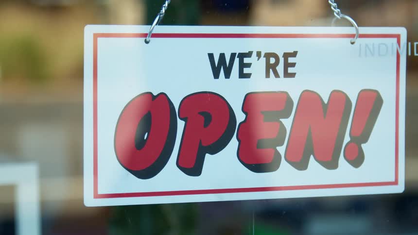 Sign hangs from a chain indicating a business is open