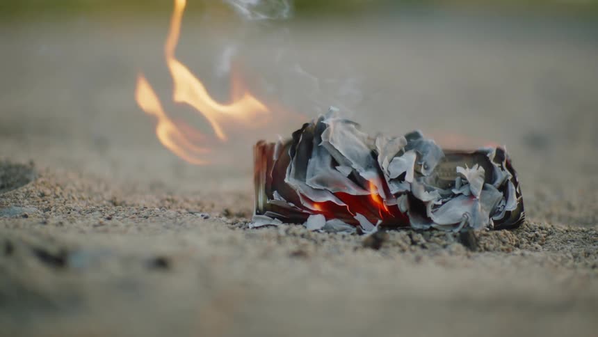 A piece of paper is on fire outdoors