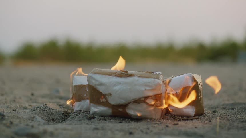 Packages on fire sitting in the dirt