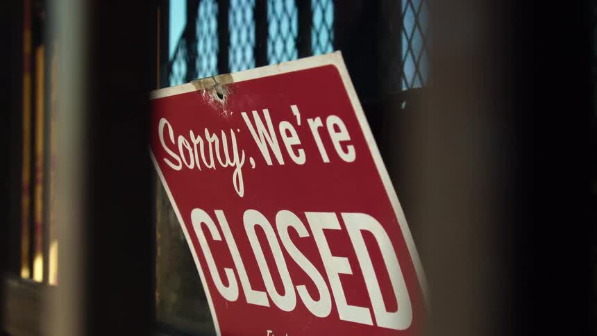 A store window that is reflecting the sky with a closed sign on it