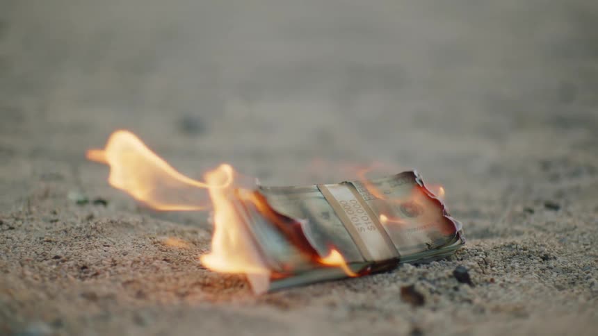 A stack of bills burning on the ground