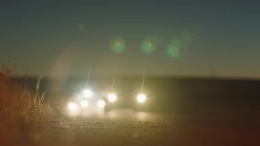 Police vehicles drive down a rural road with their lights flashing