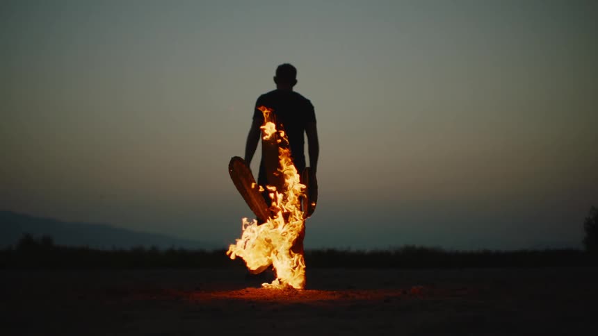 Flames surround a man as he stands on the flat land