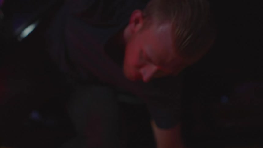 A man with a bloodied forehead stumbling out of a car and falling to the ground with a police officer and a police car in the background