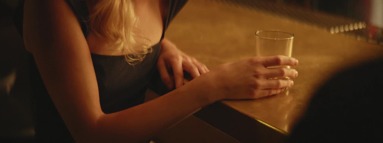 A woman sits at a bar with a drink