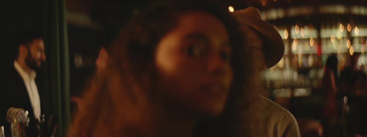 A woman walks over and sits with a man at the bar