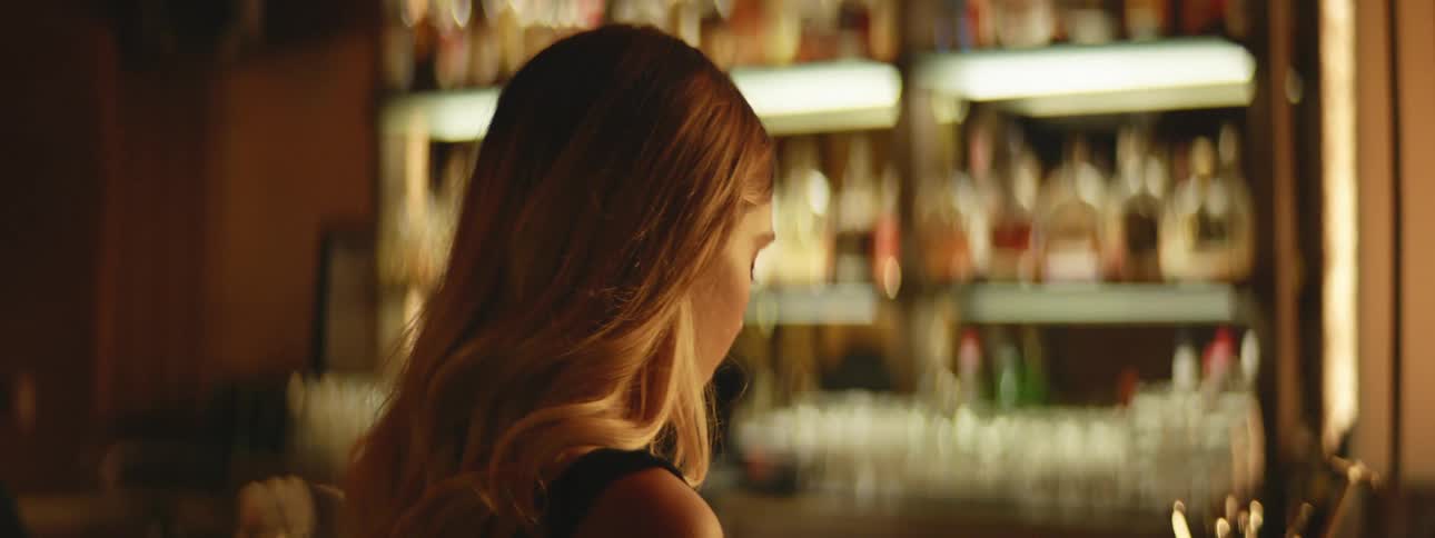 Woman turns her head as she stands at a bar
