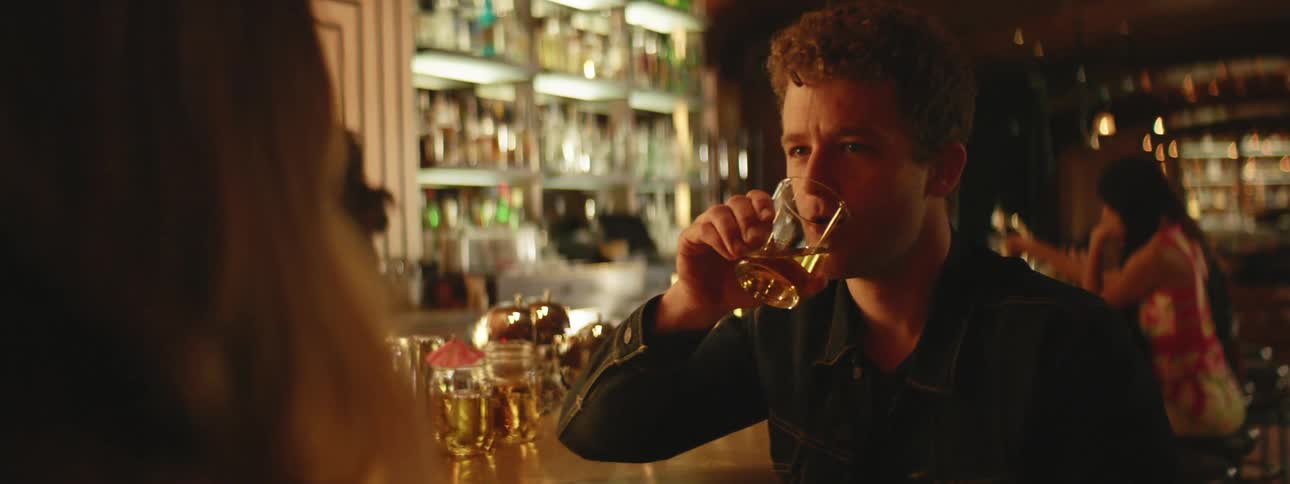 A man is talking to a woman while drinking in a bar