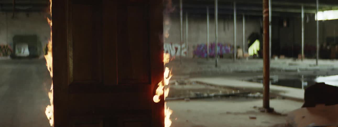 Wooden door stands in concrete floored building burning