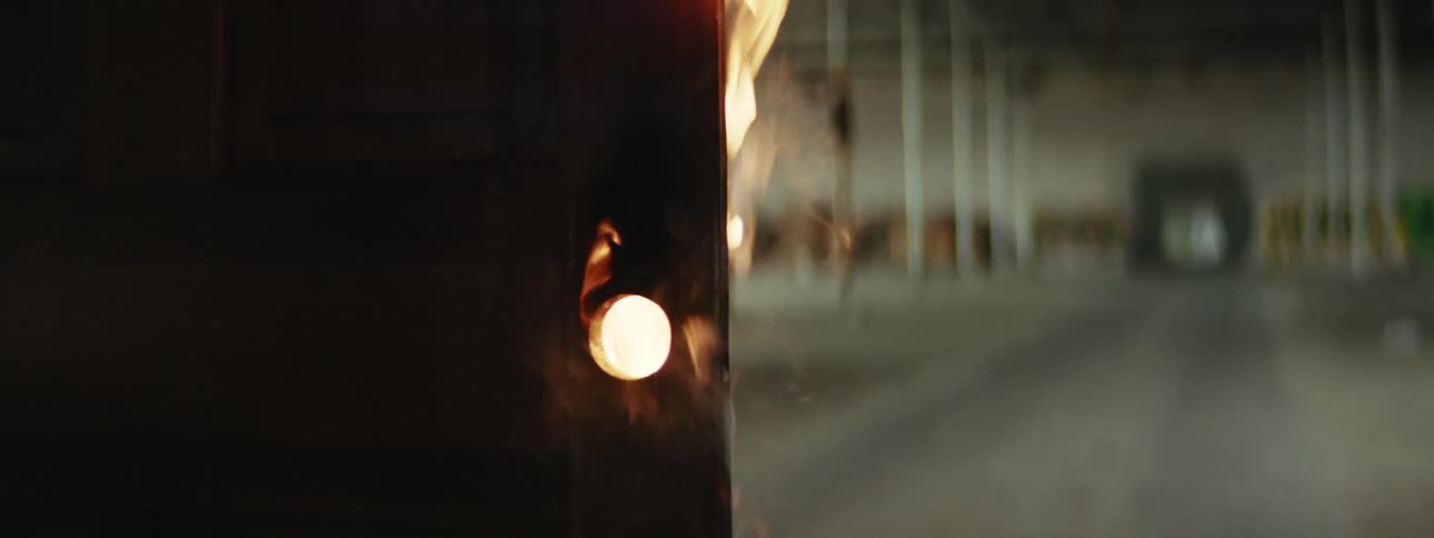 A door on fire with smoke in a warehouse with poles in the background