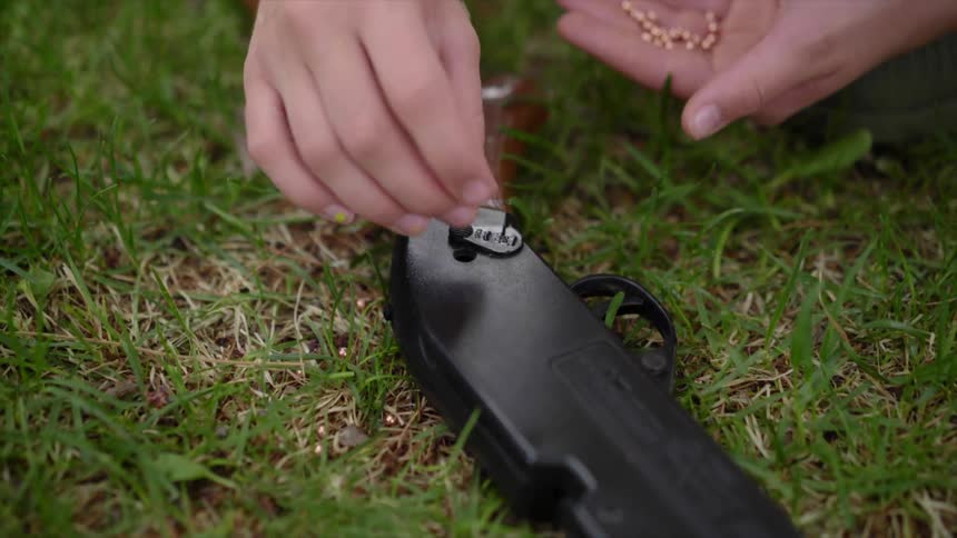 Person loads rifle laying on grass with buckshot