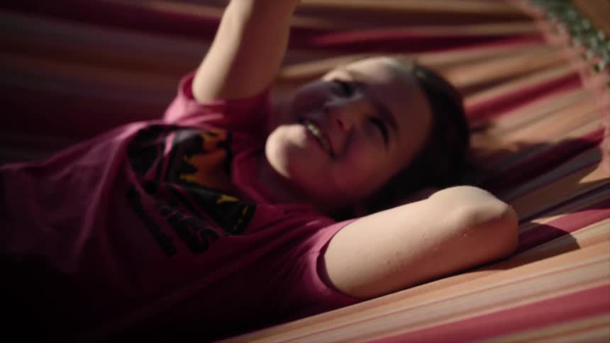 A child is laying on a hammock outdoors
